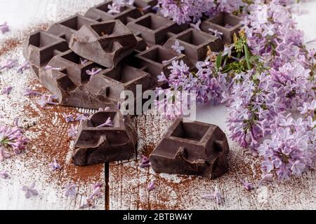 Cioccolato fondente sul tavolo con fiori liliaci Foto Stock