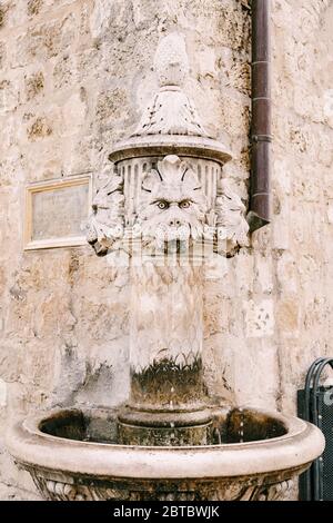 Primo piano fontana all'angolo dell'edificio, in una piazza nella città vecchia di Dubrovnik, Croazia. Una vecchia fontana in pietra potabile nella forma Foto Stock