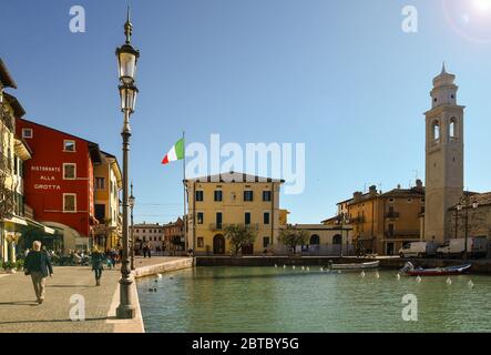 Vista retroilluminata del centro storico della città vecchia sulla riva del Lago di Garda con il porticciolo e il municipio, Lazise, Verona, Veneto, Italia Foto Stock