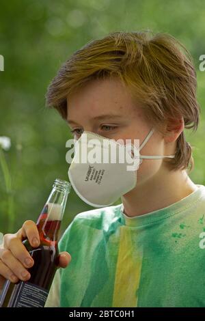 Ragazzo che indossa una maschera di respirazione cercando di bere da una bottiglia, Germania