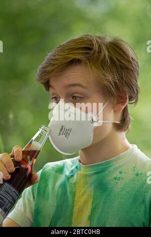 Ragazzo che indossa una maschera di respirazione cercando di bere da una bottiglia, Germania