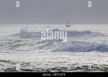 Charter pesca nella costa dell'Oregon con mare ruvido come il giorno viene a e finisce con una fitta banca nebbia sullo sfondo e cielo grigio nuvoloso Foto Stock