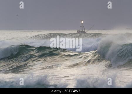 Charter pesca nella costa dell'Oregon con mare ruvido come il giorno viene a e finisce con una fitta banca nebbia sullo sfondo e cielo grigio nuvoloso Foto Stock