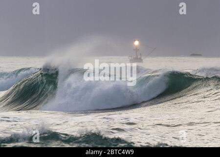 Charter pesca nella costa dell'Oregon con mare ruvido come il giorno viene a e finisce con una fitta banca nebbia sullo sfondo e cielo grigio nuvoloso Foto Stock