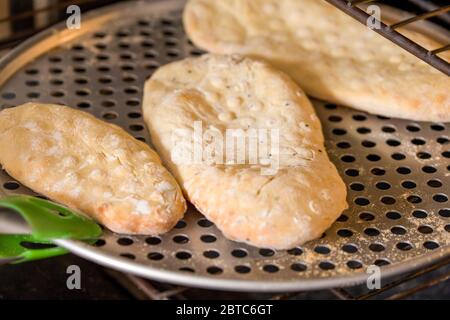 Il modo tradizionale per cuocere il Naan, un pane piatto indiano lievitato, è in un forno di terra o di argilla, ma si può cuocere su una pesante griglia di ferro o padella i Foto Stock