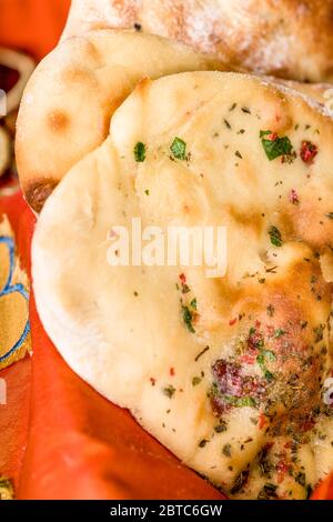 Il modo tradizionale per cuocere il Naan, un pane piatto indiano lievitato, è in un forno di terra o di argilla, ma si può cuocere su una pesante griglia di ferro o padella i Foto Stock