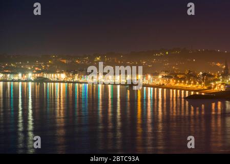 Weymouth, Dorset, Regno Unito. 24 maggio 2020. Regno Unito Meteo: Le luci dal lungomare di Weymouth in Dorset si riflettono nel mare calmo mentre la notte cala. Immagine: Graham Hunt/Alamy Live News Foto Stock