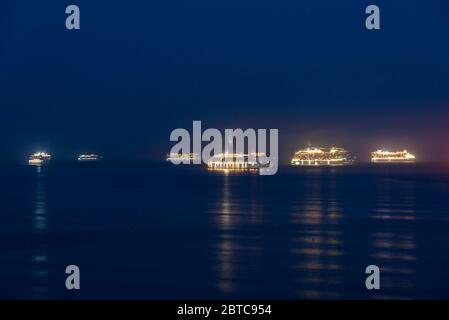 Weymouth, Dorset, Regno Unito. 24 maggio 2020. Sei delle sette navi da crociera vuote che sono ora ancorate al largo della costa di Weymouth in Dorset durante la chiusura della crociera a causa del blocco pandemico del coronavirus sono illuminate quando la notte cade. Le navi da crociera sono Arcadia, Oceana, Ventura, Aurora, Britannia e Azura, tutte gestite da P&O. Non è raffigurata la regina Vittoria di Cunard. Immagine: Graham Hunt/Alamy Live News Foto Stock