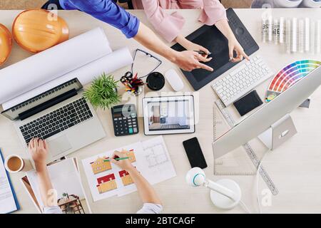 Designer che disegna il modello 3D della casa quando i colleghi discutono di schema colore per gli interni della stanza Foto Stock