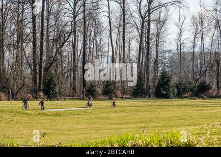 Una famiglia in bicicletta a cavallo nel parco primo giorno di primavera Foto Stock