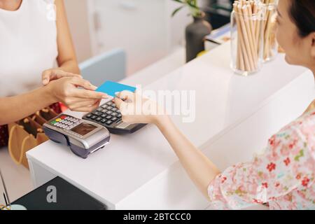 Giovane donna che paga con carta di credito per ordine in caffetteria Foto Stock