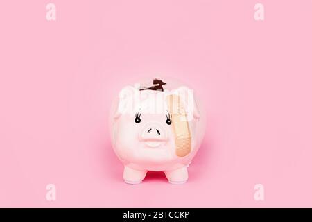 Banca Piggy rotta su sfondo rosa. Mockup, modello. Concetto di crisi finanziaria dopo la pandemia del coronavirus covid-19 Foto Stock