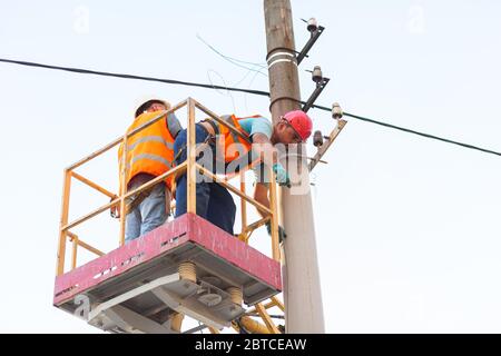 gli elettricisti sui montanti installano il supporto per la linea di alimentazione. Elettricisti professionisti lavorano sulla torre. Foto Stock