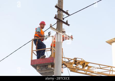 gli elettricisti sui montanti installano il supporto per la linea di alimentazione. Elettricisti professionisti lavorano sulla torre. Foto Stock