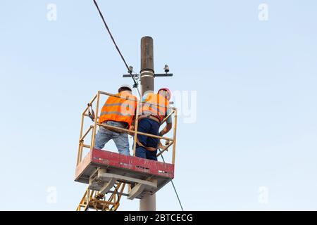 gli elettricisti sui montanti installano il supporto per la linea di alimentazione. Elettricisti professionisti lavorano sulla torre. Foto Stock