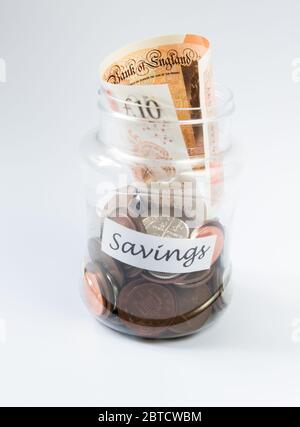 Risparmio di penny e denaro valuta di sterline britanniche in un vaso trasparente Foto Stock