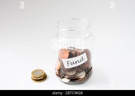 Monete all'interno del vaso etichettato Fund verso il risparmio per un investimento o spese Foto Stock