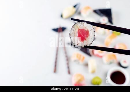 Primo piano di bastoncini di troll con porzione di sushi sopra il tavolo e sushi assortiti, salsa di soia, zenzero, wasabi. Menu sushi. Servizio di consegna in giapponese Foto Stock
