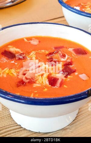 Salmorejo, zuppa spagnola di pomodoro freddo in una ciotola rustica, primo piano su un tavolo di legno Foto Stock