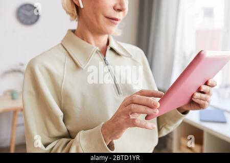 Primo piano di una donna matura che tiene un tablet digitale e guarda qualcosa su di esso Foto Stock