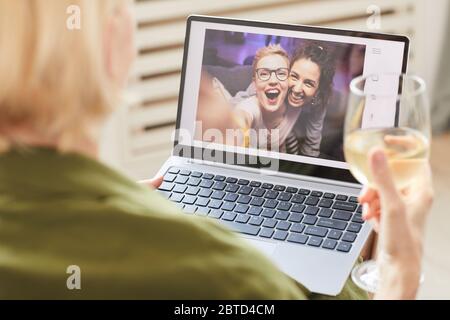 Due donne felici sul monitor del computer che parlano in linea con il loro amico che siede a casa Foto Stock