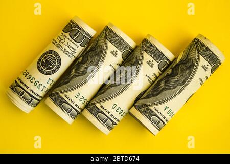 Dollari americani in rotoli. Risparmio di denaro su sfondo giallo con spazio di copia per il testo Foto Stock