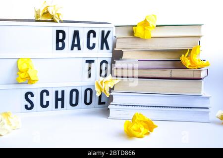 Scatola luminosa con testo DI RITORNO A SCUOLA e libri su sfondo bianco con carta gialla sbriciolata Foto Stock