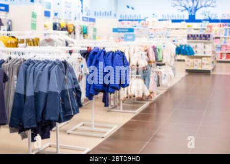 Sfocare lo sfondo, negozio di abbigliamento per bambini e articoli per bambini. Giacche e giubbotti a vento su appendiabiti, anche file di prodotti tessili, perspectivit Foto Stock