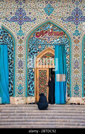 Due donne si preparano ad entrare a pregare, Imamzadeh nella città di Shahreza, provincia di Fars, Iran Foto Stock