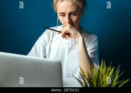 Donna concentrata guardando lo schermo del notebook. Concetto di formazione, acquisti online, lavoro remoto e altri significati Foto Stock