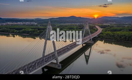 Budapest, Ungheria - Vista panoramica aerea del ponte sospeso Megyeri al tramonto con il cielo blu e dorato e le nuvole Foto Stock