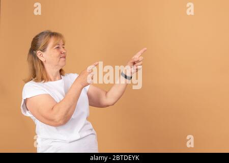 Felice vecchia donna che mostra al copyspace spazio vuoto. Sorridente anziana femmina che tiene le dita puntano a sinistra per vuoto il posto per il testo Foto Stock