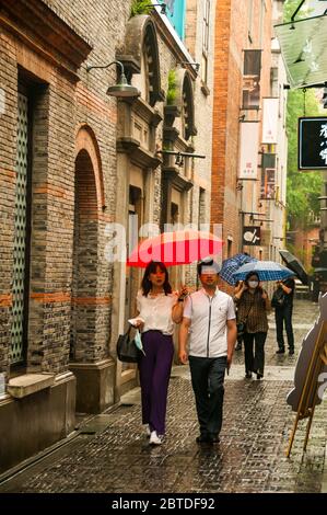 I turisti esplorano i vicoli sullo Xintiandi di Shanghai in una giornata di primavera piovosa. Foto Stock