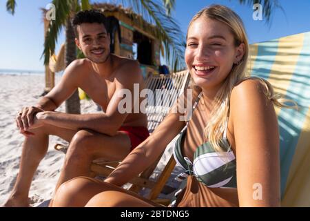 Coppia caucasica seduta su sedie a sdraio in spiaggia Foto Stock