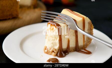 Mangiare gustosa cheesecake con salsa al caramello, vista del guardaroba Foto Stock