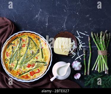 quiche appena sfornate con asparagi di salmone ripieno su un tavolo di cemento con ingredienti, primo piano, vista orizzontale dall'alto, piatto, libero s Foto Stock