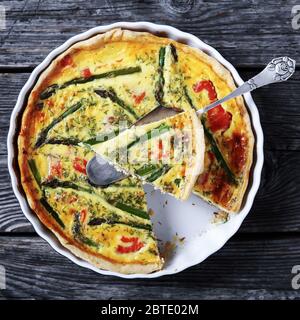 quiche con asparagi di salmone ripieno tagliato a fette in una teglia su un vecchio tavolo di legno, primo piano, vista orizzontale dall'alto, piatto Foto Stock