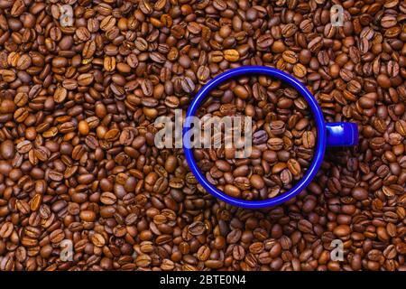 Tazza di teglia blu piena di chicchi di caffè. Commercio Equo E Solidale. Commercio di materie prime. Chicchi di caffè freschi. Foto Stock