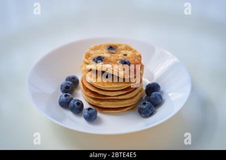 Frittelle di ricotta al mirtillo su fondo bianco. Tonificazione. Fuoco selettivo. Foto Stock