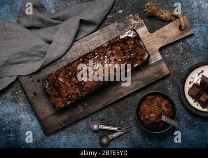 Torta fatta in casa con cialde di cioccolato con condimento e glassa su pane rustico in legno da taglio. Vista dall'alto. Fotografia di cibo scuro. Foto Stock