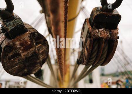 Pulegge e corde di legno a bordo della nave alta e della nave da addestramento polacca quadrata Dar Mlodziezy durante la corsa delle navi alte a Greenock, Scozia Foto Stock