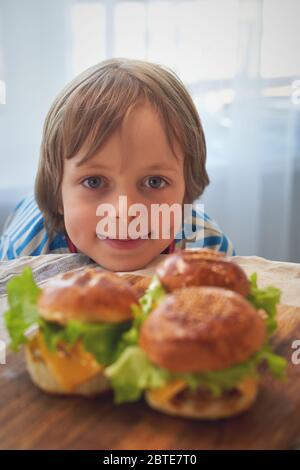 Primo piano di caucasico ragazzo mangiare hamburger al barbecue Foto Stock