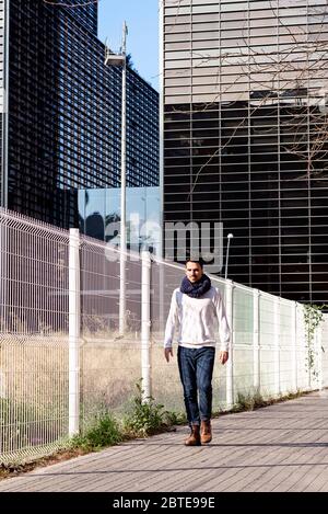 Giovane abbigliamento informale uomo a piedi sulla strada contro il quartiere degli affari Foto Stock