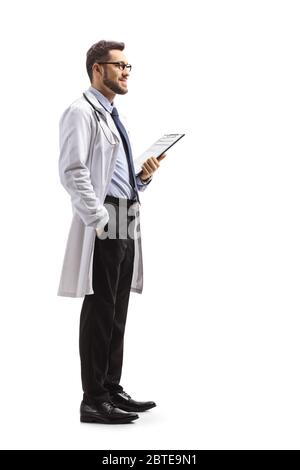 Foto di profilo a lunghezza intera di un giovane medico maschile che tiene una clipboard isolato su sfondo bianco Foto Stock