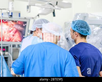 Un gruppo di chirurghi in un'uniforme medica supervisiona le apparecchiature mediche. Il processo di esecuzione di un intervento chirurgico utilizzando un moderno sistema robotico Foto Stock