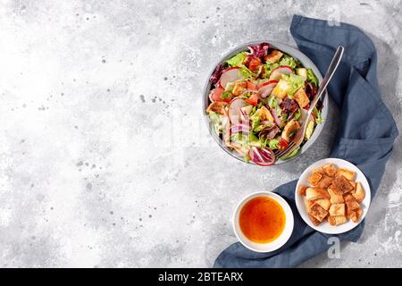 Insalata tradizionale di Fattoush mediorientale con pane pita, verdure fresche e salsa di sumac al limone su sfondo grigio vista dall'alto Foto Stock