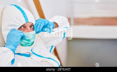 Infermiere o medico che indossa indumenti protettivi mette su nuova maschera facciale durante l'epidemia di Covid-19 Foto Stock