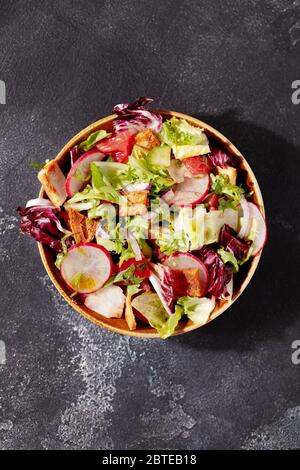 Insalata tradizionale di Fattoush mediorientale con pane pita, verdure fresche e salsa di sumac al limone su sfondo grigio scuro vista dall'alto Foto Stock