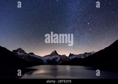 Notte incredibile vista del lago Bachalpsee nelle Alpi Svizzere montagne. Cime innevate del Wetterhorn, Mittelhorn e Rosenhorn sullo sfondo. Valle di Grindelwald, Svizzera. Paesaggio la fotografia astronomica Foto Stock