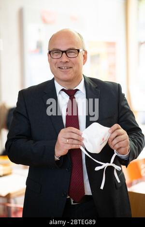 Amburgo, Germania. 25 Maggio 2020. Ties Rabe (SPD), senatore per le scuole e la formazione professionale ad Amburgo, tiene la sua bocca e il naso con il logo di Amburgo durante una sessione fotografica presso la scuola primaria Wielandstraße. Dopo tre mesi di vacanze e lezioni online, tutti gli studenti di Amburgo vedranno di nuovo i loro insegnanti questa settimana. Lunedì, Rabe ha accettato le prime maschere di una donazione di un totale di 50,000 maschere dalla società di posta-ordine online su di voi presso la scuola elementare nel distretto di Eilbek. Credit: Christian Charisius/dpa/Alamy Live News Foto Stock